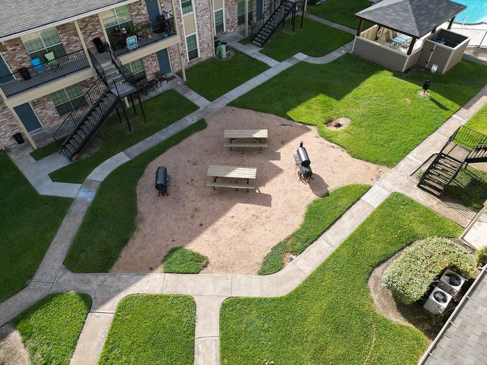 Inviting apartment courtyard featuring picnic tables, barbecue grills, and a cozy gazebo amidst lush greenery.