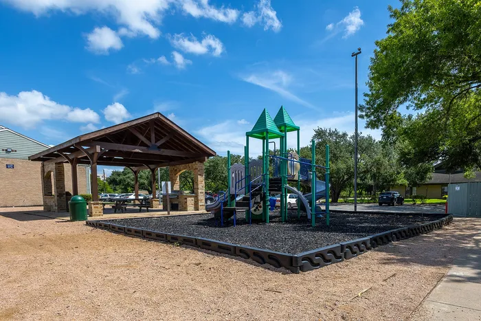 Charming community playground with vibrant slides and a cozy covered picnic area under a sunny blue sky.