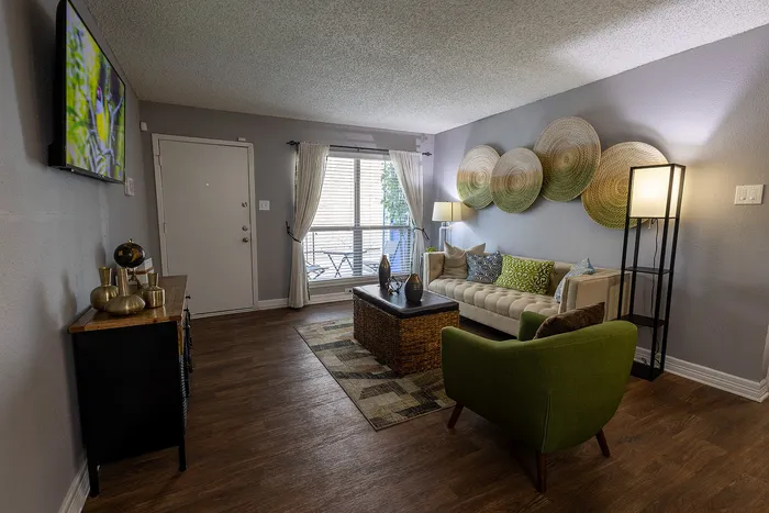 Cozy living room with stylish decor, featuring vibrant green armchair, elegant wall accents, and large window for natural light.