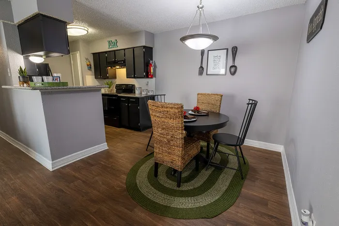 Charming dining area with stylish rattan chairs, a circular table, and a cozy kitchen with modern appliances.