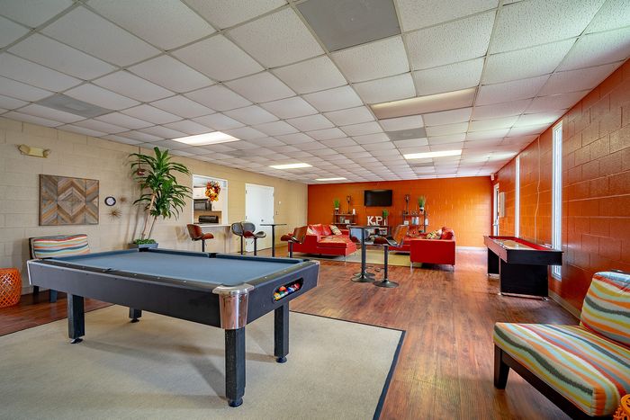Vibrant recreational space featuring a sleek pool table, modern seating area with red couches, and vibrant decor accents.