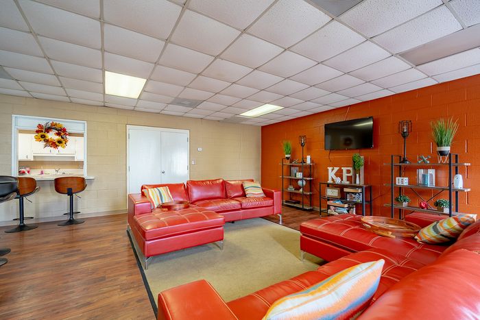 Vibrant living room with bold red leather couches, stylish shelving, and a cozy bar area; perfect for entertaining.