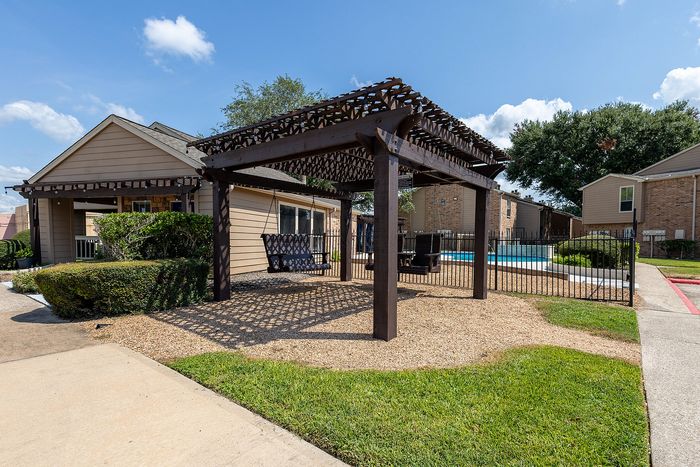Inviting outdoor area with a charming pergola, swings, and a sparkling pool, ideal for relaxation and enjoying sunny days.