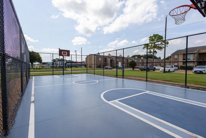 Vibrant community basketball court with lush surroundings and nearby residential buildings, perfect for active outdoor living.