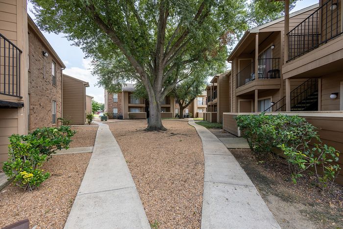 Charming apartment courtyard with lush greenery, mature trees, and well-maintained pathways, creating a serene living environment.