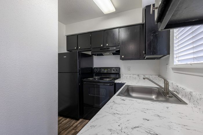 Modern kitchen with sleek black appliances, elegant marble countertops, and ample cabinet space, perfect for culinary creativity.