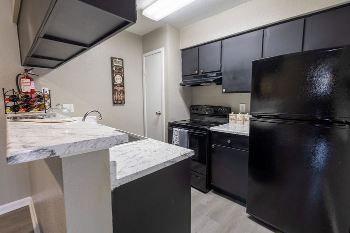 Modern kitchen with sleek black appliances, stylish marble countertops, and ample cabinet space.