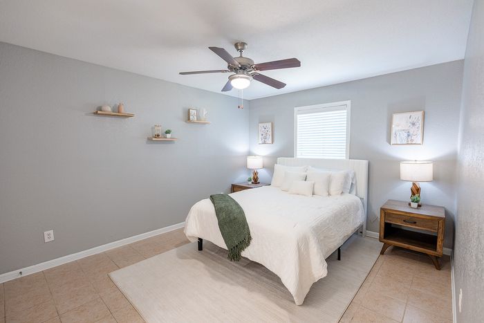 Bedroom at Huntington Oaks Apartments in Alvin, TX with ceiling fan and natural light.