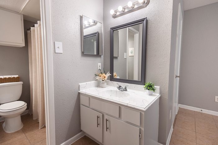 Bathroom sink and mirror at Huntington Oaks Apartments in Alvin, TX.