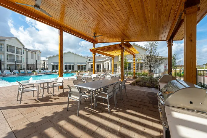 Covered outdoor kitchen and grilling area with seating near the pool at Lakeview at Westpark apartments in Richmond, TX
