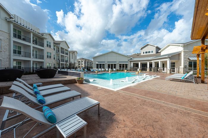 Apartment community exterior with resort-style pool and lounge seating at Lakeview at Westpark in Richmond, TX