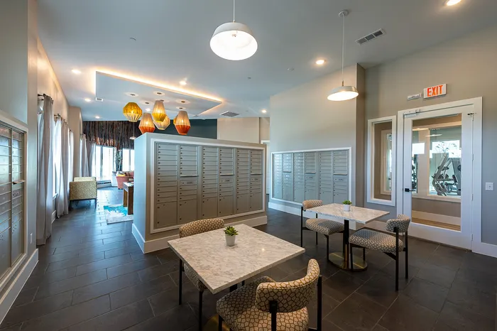 Modern apartment lobby with elegant seating, unique hanging light fixtures, and convenient mailboxes.