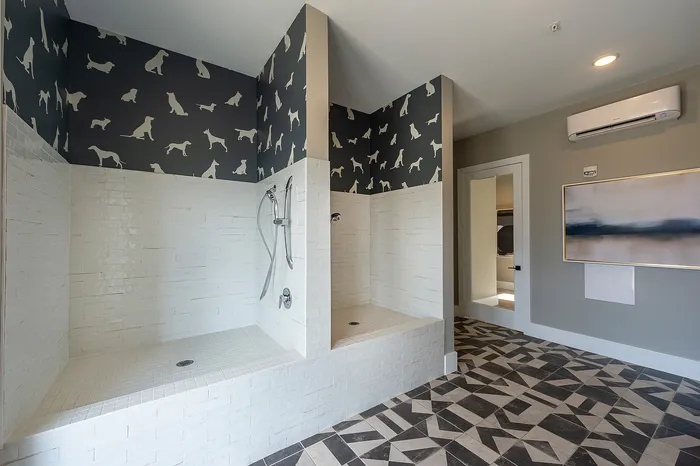 Modern bathroom featuring unique dog-themed wallpaper, dual shower setup, and stylish geometric floor tiles.