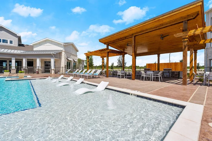Luxurious outdoor pool area featuring stylish stone architecture, relaxing sun loungers, and a chic wooden pergola for shaded seating.