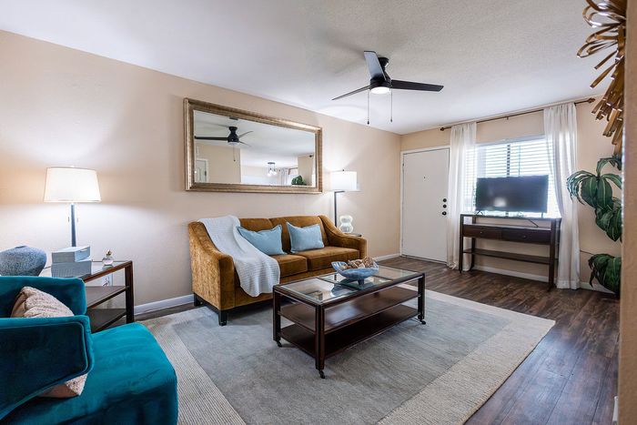 Spacious living room with wood-style flooring, ceiling fan, and natural light at Waterchase Apartments in Humble, TX