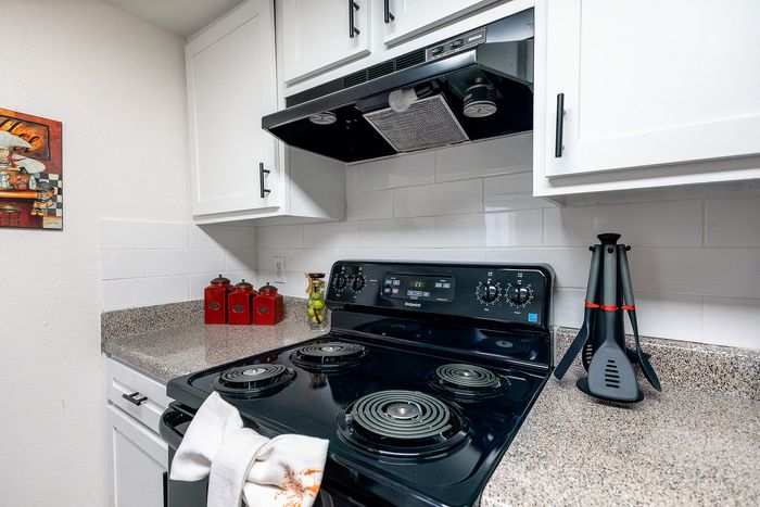 Kitchen with electric range, vent hood, and updated cabinetry at Waterchase Apartments in Humble, TX
