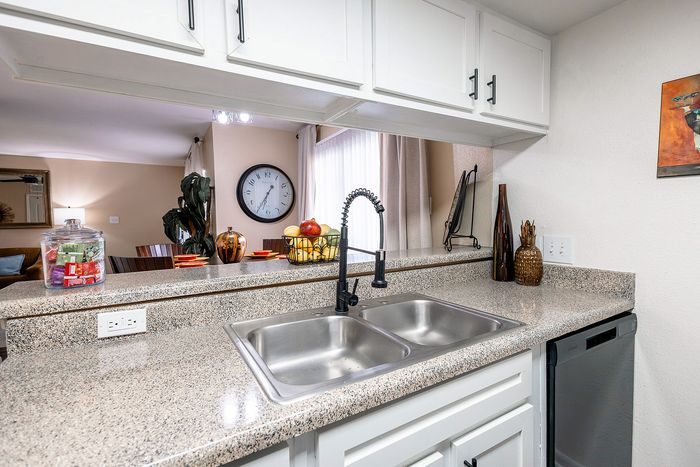 Kitchen pass-through with double sink overlooking living area at Waterchase Apartments in Humble