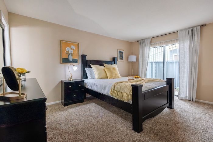 Large primary bedroom with natural light and carpet flooring at Waterchase Apartments in Humble