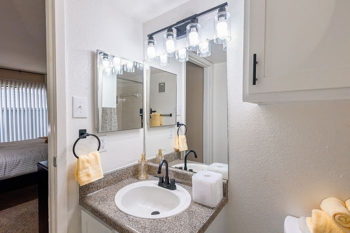 Bathroom vanity with modern lighting and updated fixtures at Waterchase Apartments in Humble, TX