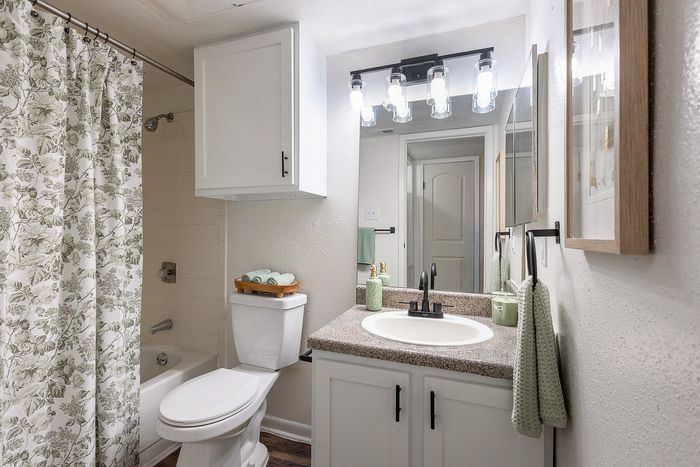 Bathroom vanity with modern lighting and updated fixtures at Waterchase Apartments in Humble, TX