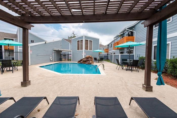 Swimming pool with lounge seating and shaded pergola at Waterchase Apartments in Humble, TX