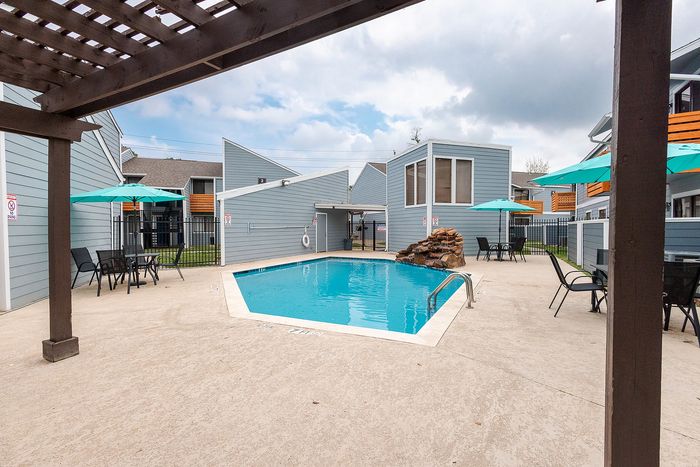 Pool area with pergola seating and outdoor tables at Waterchase Apartments in Humble