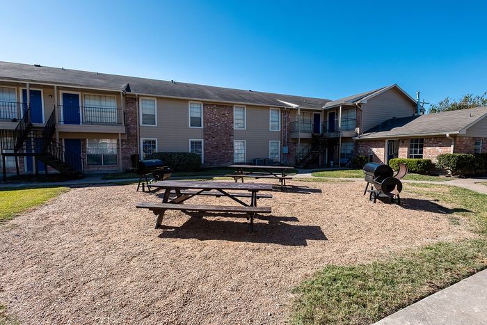 Courtyard with picnic tables and grilling area at Steeplechase Apartments in Alvin TX