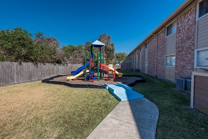 Playground area with slides and seating at Steeplechase Apartments in Alvin TX