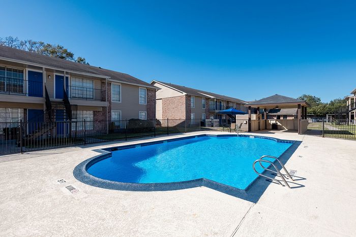 Close view of swimming pool with lounge and shaded seating area in Alvin TX apartment community