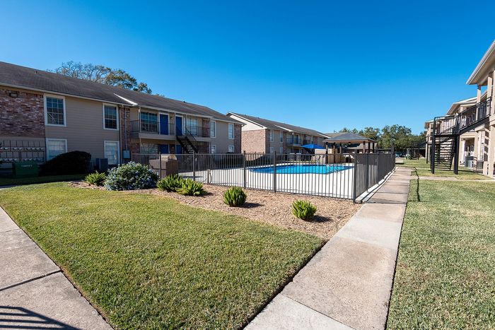 Landscaped walkway and pool area at Steeplechase Apartments in Alvin TX