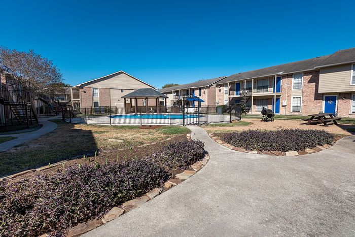 Wide view of pool courtyard with landscaped paths at Steeplechase Apartments in Alvin TX