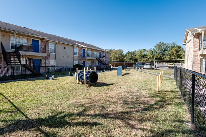 Fenced dog park with agility features at Steeplechase Apartments in Alvin TX