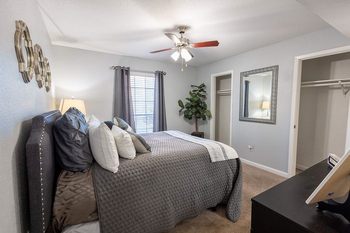 Large bedroom with ceiling fan, walk-in closet access, and modern staging