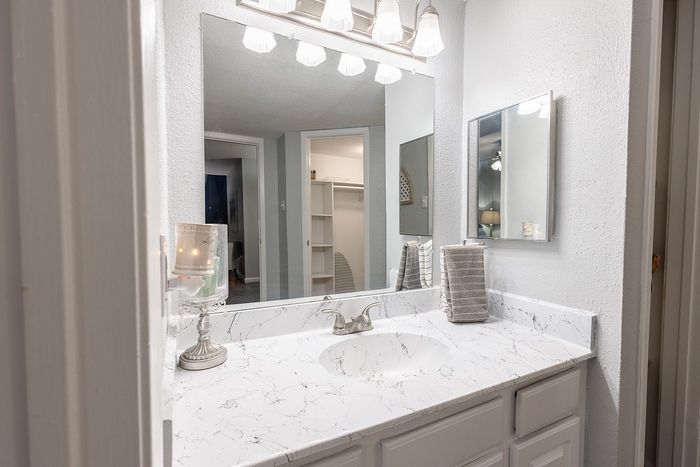 Bathroom vanity with updated countertop, modern fixtures, and mirror lighting