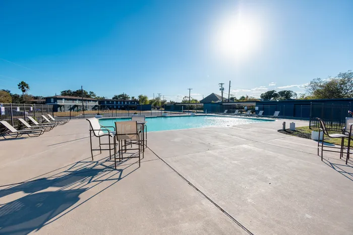 Inviting apartment swimming pool area with sun-drenched lounging chairs and scenic views, creating a perfect relaxation spot.