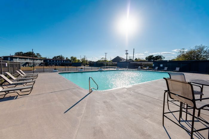 Inviting outdoor swimming pool with sunlit water surrounded by comfortable lounge chairs, perfect for relaxation and leisure.