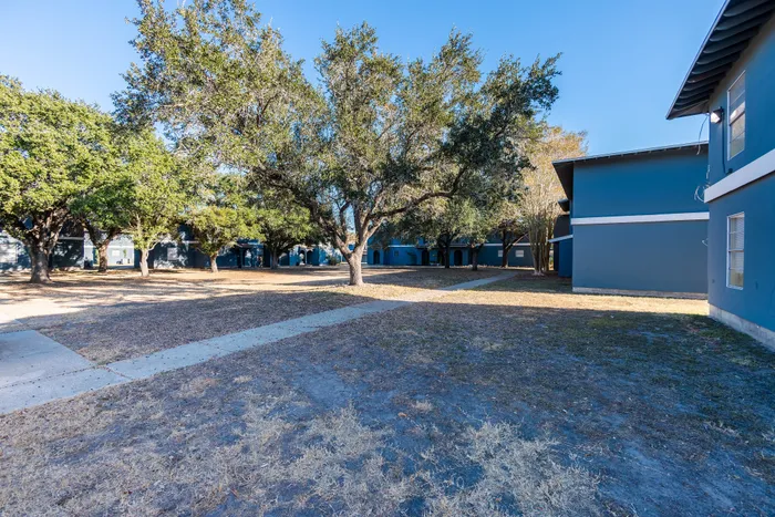 Charming apartment complex surrounded by verdant trees and open pathways, offering serene and inviting outdoor spaces.