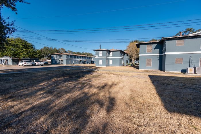 Charming apartment complex featuring modern two-story buildings with ample parking and open outdoor space, under a clear blue sky.
