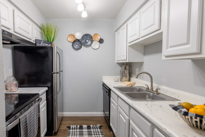 Modern kitchen with sleek stainless steel appliances, elegant marble countertops, and crisp white cabinetry.