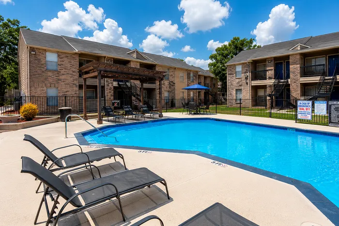 Apartment community swimming pool with lounge chairs at Green Meadows Apartments in Houston TX