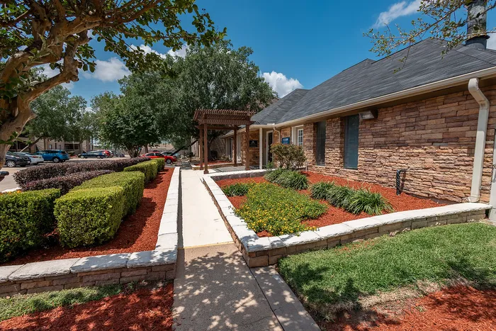 Leasing office exterior with landscaped entrance at Green Meadows Apartments in Houston TX
