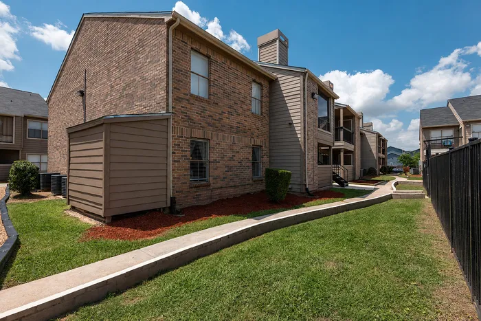 Apartment building exterior with landscaped green space at Green Meadows Apartments in Houston TX