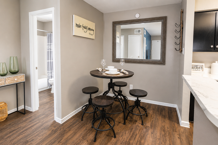 Dining area and open-concept apartment layout at Newport Oaks Apartments in Alvin, TX with modern finishes and wood-style flooring.