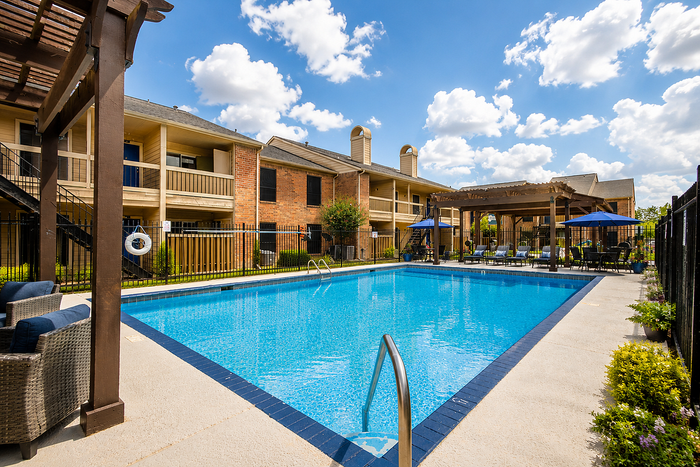 Spacious outdoor swimming pool with pergola seating at Brookmore Hollow Apartments in Rosenberg, Texas.