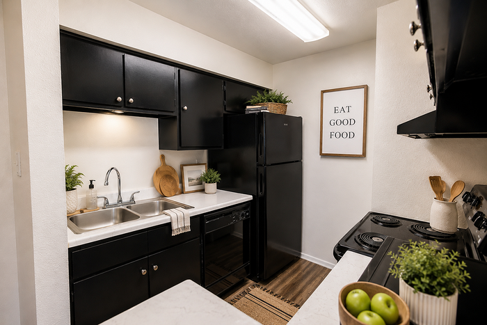 Bright apartment kitchen with black cabinetry, quartz-look countertops, dishwasher, and refrigerator at Brookmore Hollow Apartments
