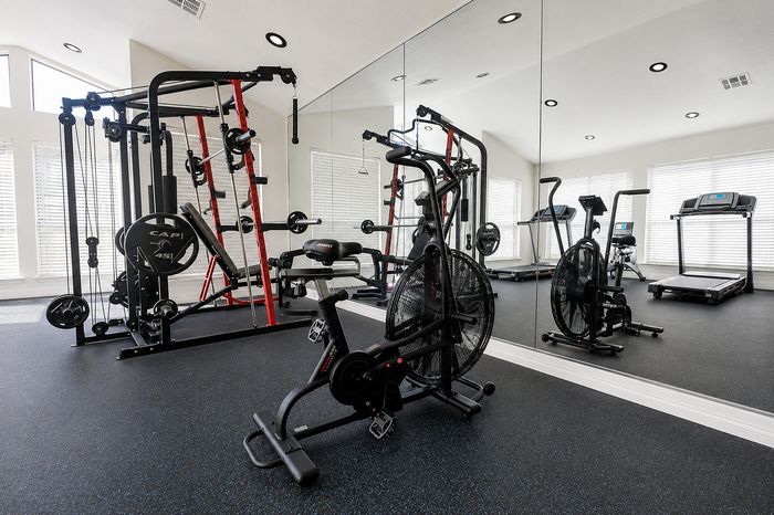 Deerbrook Gardens fitness center in Humble, TX with treadmill, rowing machine, strength equipment and mirrored workout space.