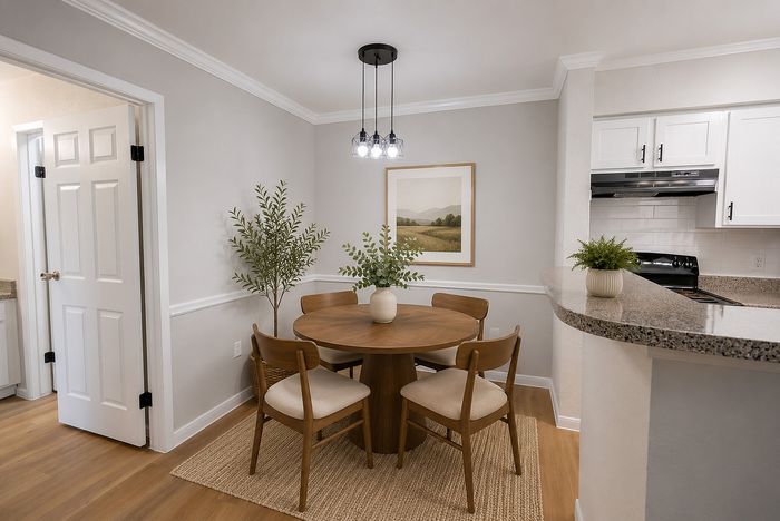 Dining area at Deerbrook Gardens in Humble, TX with a round wood dining table, four chairs and adjacent kitchen breakfast bar.