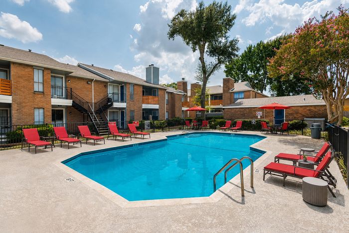Aerial view of the Deerbrook Gardens swimming pool in Humble, TX with organized poolside seating, umbrellas and landscaped grounds.