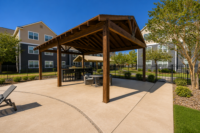 Inviting outdoor patio with stylish wooden pergola, perfect for relaxing or entertaining at the modern apartment complex.