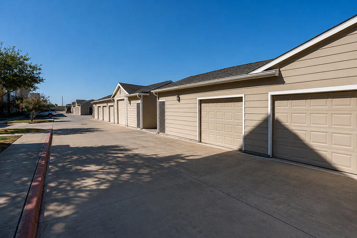 Charming townhouse exterior with modern garage doors and a clean, spacious driveway under clear blue skies.